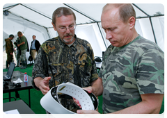 Vycheslav Rozhnov, a deputy director of the Severtsov Institute of Ecology and Evolution, showing Vladimir Putin a satellite-tracked collar with a GPS navigator which researchers fasten around the captured tiger’s neck