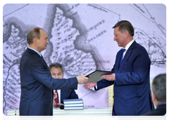 Vladimir Putin presents Sergei Ivanov with a membership certificate of the Russian Geographical Society’s Board of Trustees