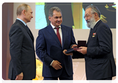 Vladimir Putin and Sergei Shoigu presenting the Grand Gold Medal to Professor Artur Chilingarov, Doctor of Geography, correspondent member of the Russian Academy of Sciences and First Vice President of the Russian Geographical Society